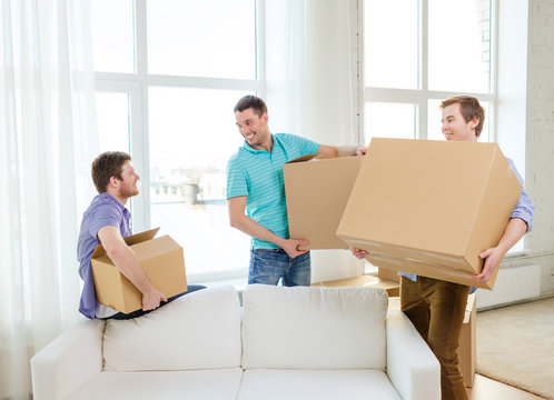 Smiling Male Friends Carrying Boxes At New Place