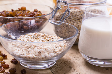 Bowl of oats, raisins cup of milk on the wooden table