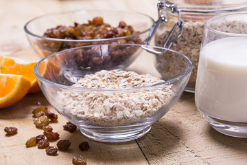 Bowl of oats, raisins cup of milk on the wooden table