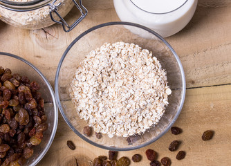 Bowl of oats, raisins cup of milk on the wooden table