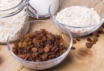 Bowl of oats, raisins cup of milk on the wooden table