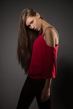 Beautiful young model in red posing on dark background.