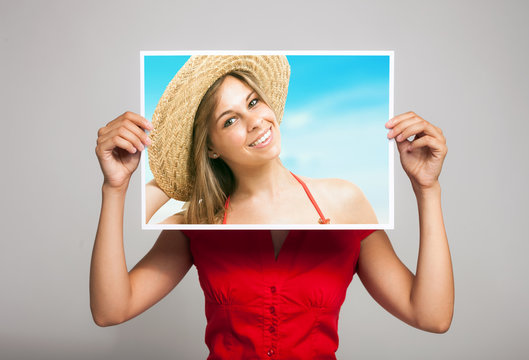 Woman holding a portrait of herself in a tropical beach