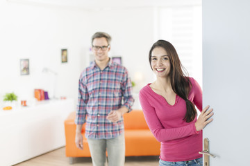 Fototapeta premium couple standing at front door to invite people at home