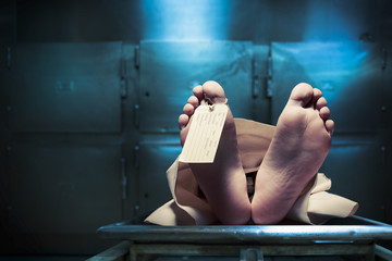 Feet on a morgue table with toe tag with dramatic lighting