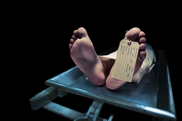 Feet on a morgue table with toe tag with dramatic lighting