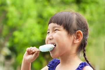 happy little girl eating popsicle at summertime