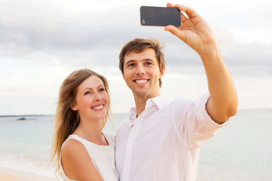 Couple taking a selfie on the beach at sunset