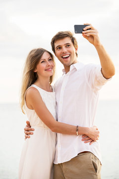 Couple taking a selfie on the beach at sunset