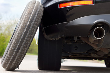 Spare tyre balanced against a car