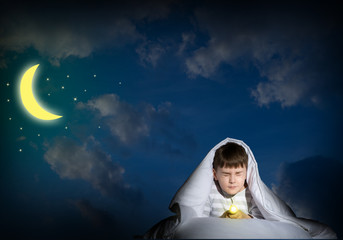 boy under the covers with a flashlight