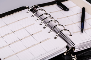 Personal organizer or planner with pen on white background