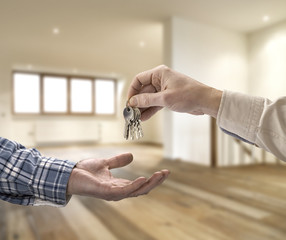 Realtor giving house key to buyer in empty room