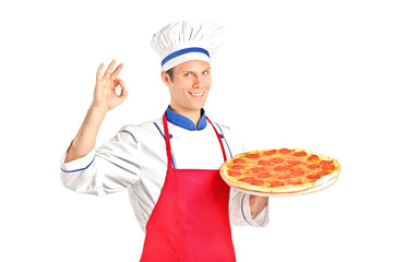 Male chef holding a pizza and gesturing with hand