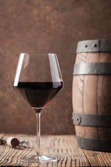 Glass with red wine and old barrel.