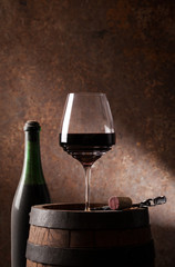Glass with red wine and old barrel.