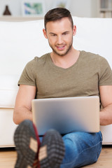 junger mann sitzt mit laptop auf dem boden
