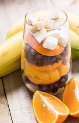 Glass of mixed fresh fruits and raisins with the wholes bananas