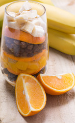 Glass of mixed fresh fruits and raisins with the wholes bananas