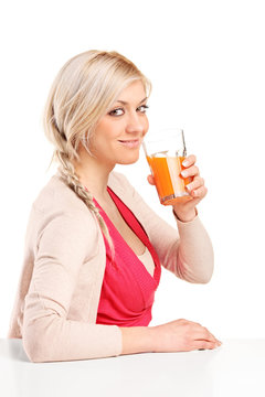 Girl sitting at table and drinking orange juice