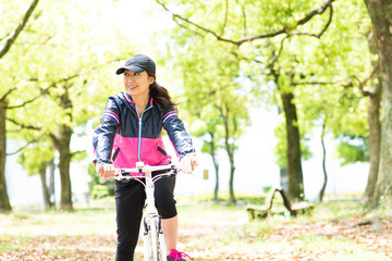 Naklejka premium 自転車に乗って森の中をサイクリングする日本人女性