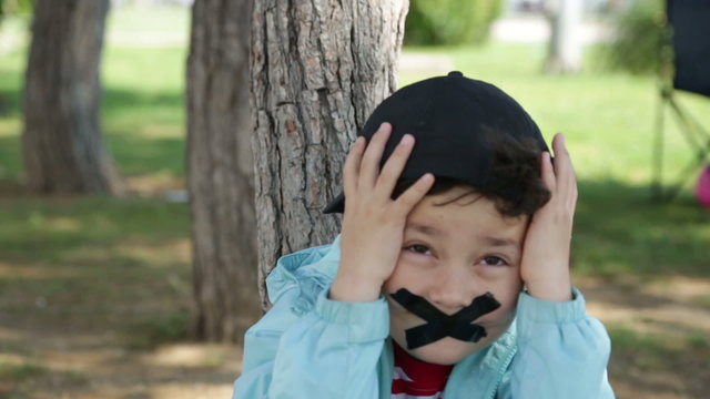 chatty child covers his mouth with sellotape