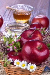 apples in a basket with honey and flowers on wooden table