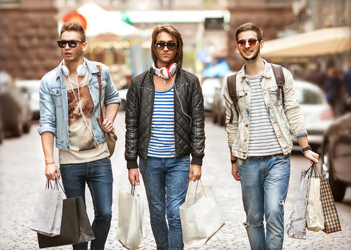 Fashion young guys go shopping with many colored shopping bags