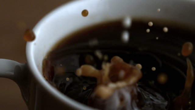 Milk drop falling into coffee cup