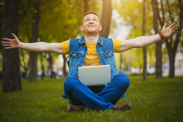 Fototapeta premium young man in the park lying on grass with laptop