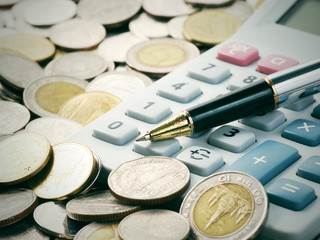 Old dusty ball pen on calculator with stack coins background