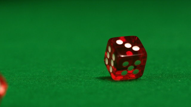 Red dice rolling on casino table