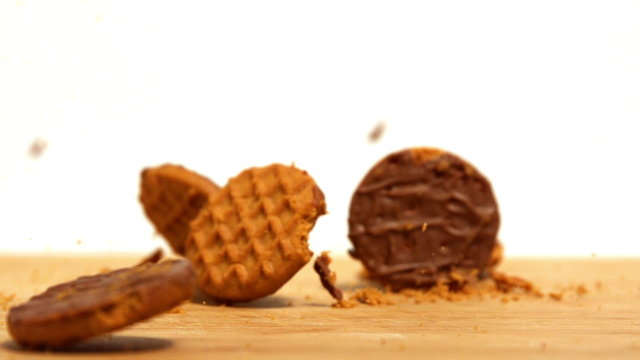 Biscuits falling and breaking on wooden table