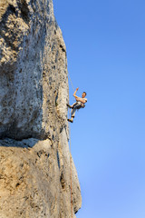 Extreme rock climbing, man on natural wall with blue sky.