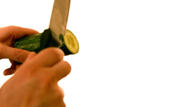 Hand slicing a cucumber on white background