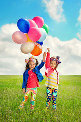 Children with balloons walking on spring field