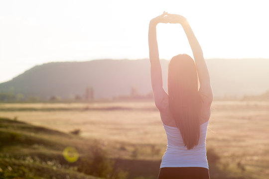 cheering woman open arms to sunrise