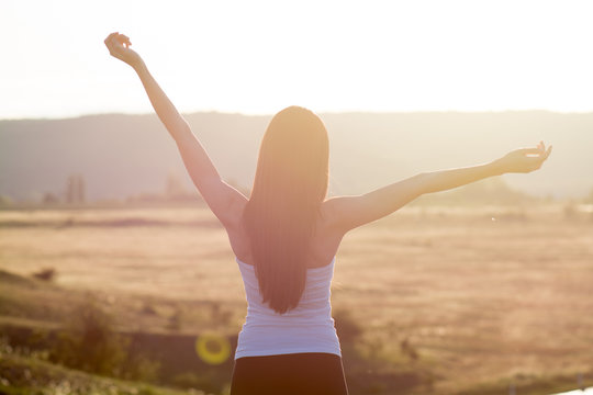 cheering woman open arms to sunrise