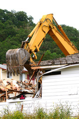 A large track hoe excavator tearing down an old hotel to make wa