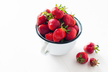 strawberries in white enamel mug