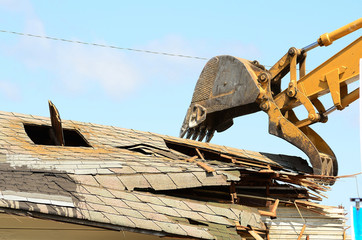 A large track hoe excavator tearing down an old hotel to make wa