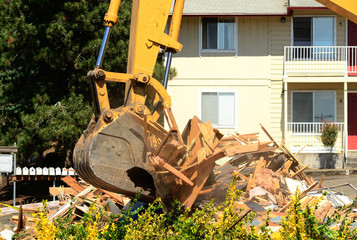 A large track hoe excavator tearing down an old hotel to make wa