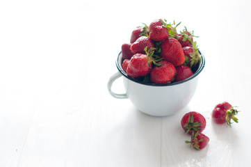 strawberries in white enamel mug
