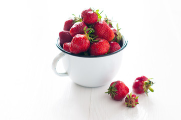 strawberries in white enamel mug
