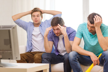 sad male friends with vuvuzela watching sports