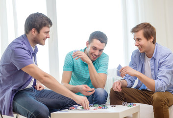 happy three male friends playing poker at home