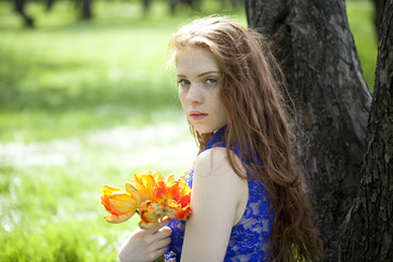 Fototapeta premium Young girl in a blue dress relaxing in spring park