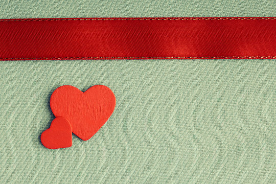 Red wooden decorative hearts on gray cloth background.