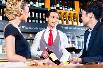 Asian couple tasting red wine in bar