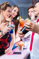 Freunde feiern mit Barkeeper in Cocktailbar